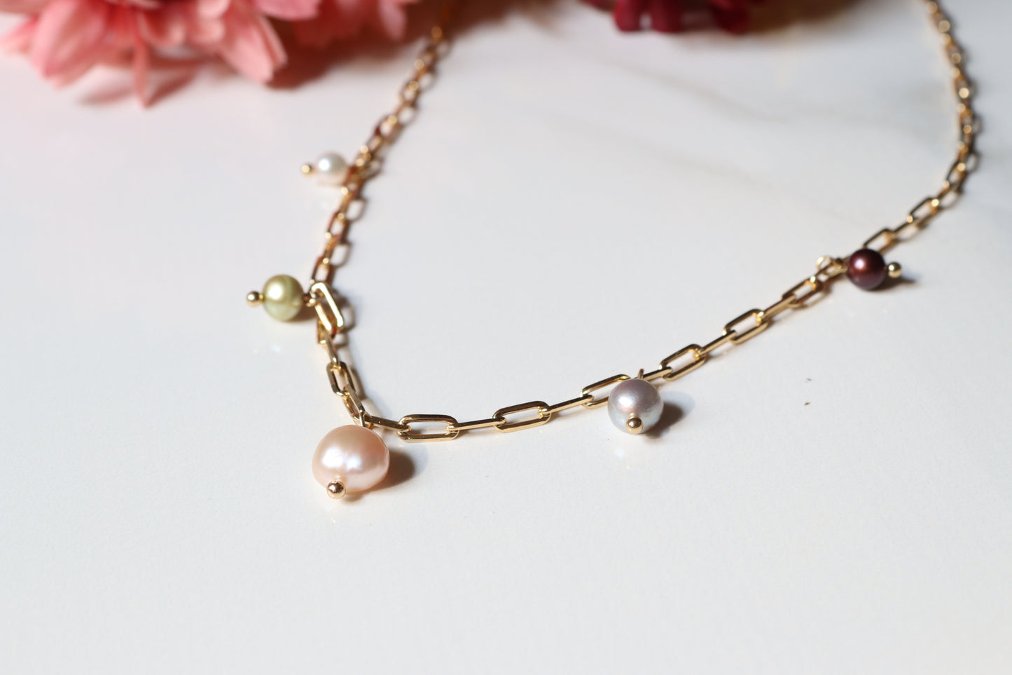 Gold chain necklace with pearls on a light background